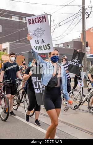 Toronto, Ontario, Canada. 6 Giugno 2020. Durante la manifestazione un protetore che indossa una maschera facciale tiene un cartello.la morte di George Floyd, mentre nella custodia della polizia di Minneapolis ha scatenato proteste in tutto il paese, così come dimostrazioni di solidarietà in tutto il mondo. Credit: Shawn Goldberg/SOPA Images/ZUMA Wire/Alamy Live News Foto Stock