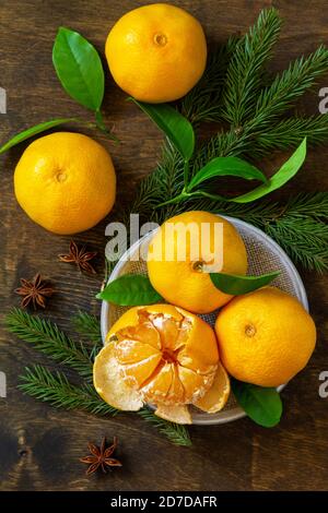 Frutta invernale. Freschi e succosi mandarini clementini con foglie su rustico tavolo di legno. Vista dall'alto sfondo piatto. Foto Stock