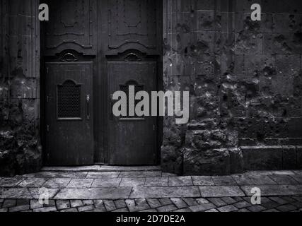 Immagine in bianco e nero edizione scura.shrapnel impatto contro una parete E l'antica porta del tempio San Filippo Neri a Barcellona Spagna Foto Stock