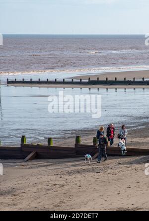 Withernsea, East Yorkshire, England, 20/10/2020 - amici che camminano con i cani più lidi sulla spiaggia con acqua di rottura. Foto Stock