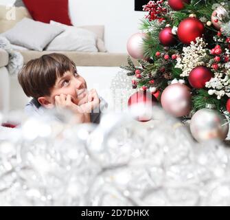 ritratto di bambino sorridente vicino all'albero di natale decorato con palle, confortevole in soggiorno Foto Stock