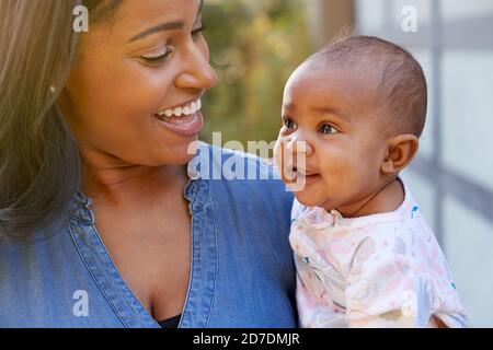 Sorridente madre afroamericana coccolandosi e giocando con la figlia del bambino In giardino a casa Foto Stock