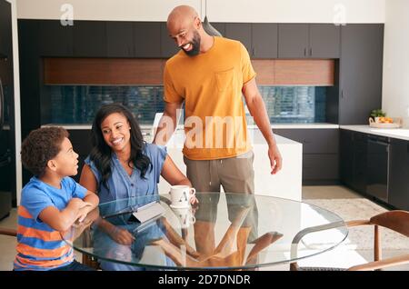 Genitori afroamericani aiutare Son studiare lavoro sul tablet digitale In cucina Foto Stock