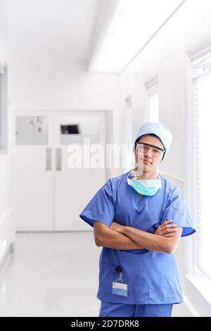 Ritratto di giovane medico maschile indossando scrub in piedi in ospedale Corridoio Foto Stock