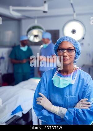 Ritratto di chirurgo femminile che indossa scrub e occhiali protettivi Sala operatoria dell'ospedale Foto Stock