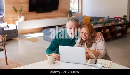 Coppia ispanica senior a casa seduta a tavolo con laptop Insieme Foto Stock
