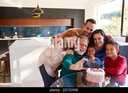 Multi-generazione Famiglia ispanica prendendo Selfie per celebrare il compleanno delle nipoti a. Casa Foto Stock