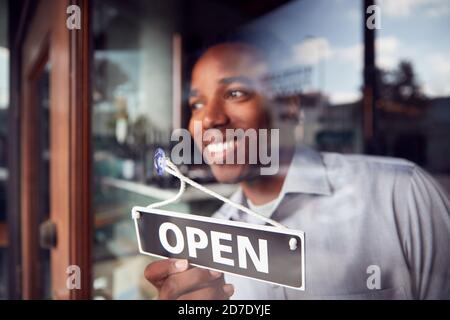 Uomo proprietario di Start Up Coffee Shop o Ristorante Turning Cartello rotondo aperto sulla porta Foto Stock