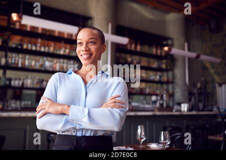 Ritratto di fidata donna Proprietario del Ristorante Bar Standing by Contatore Foto Stock