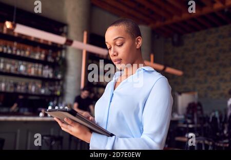 Donna sicura proprietaria del Ristorante Bar in piedi da Counter Holding Tablet digitale Foto Stock