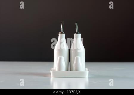 set di bottiglie bianche di aceto e olio di porcellana, shaker per sale e pepe sul tavolo da cucina, primo piano Foto Stock