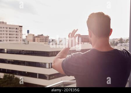 Vista posteriore di Man scattare foto di skyline della città contro Sole flaring Foto Stock