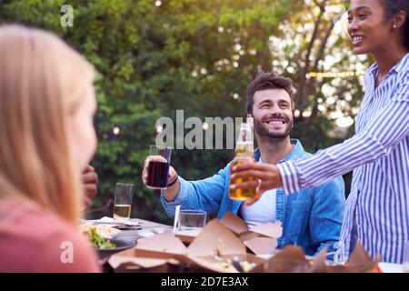 Amici fare brindisi con alcol in Giardino a casa godendo Festa estiva del giardino Foto Stock