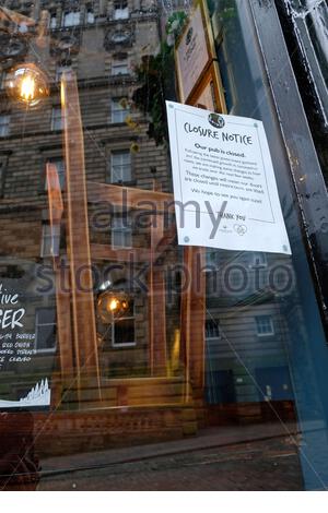 Edimburgo, Scozia, Regno Unito. 22 ottobre 2020. Le attuali restrizioni del Covid-19, che includono la chiusura di tutti i pub, bar e ristoranti della zona centrale, saranno prorogate oltre il 26 ottobre come previsto e rimarranno in vigore per un'altra settimana fino a lunedì 2 novembre. Avviso di chiusura sulla finestra del pub chiuso a chiave e con sedie impilate sui tavoli. Credit: Craig Brown/Alamy Live News Foto Stock