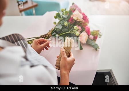 Specialista floreale professionista che si piega un filo per fissare un bouquet Foto Stock