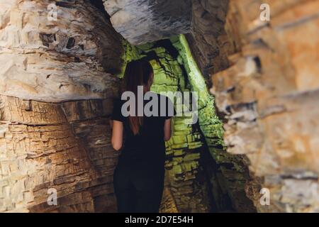 Giovane donna in piedi di fronte a una pietra roccia all'aperto. Foto Stock