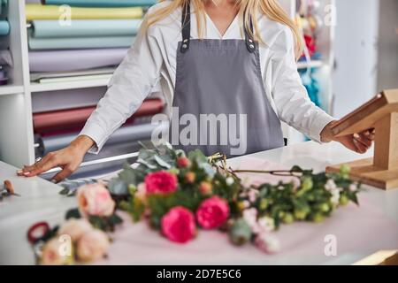 Donna elegante che indossa un grembiule in uno studio di fiori Foto Stock