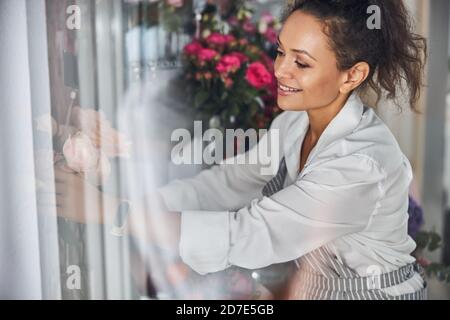 Fiorista qualificato mettendo con cura mazzi di fiori su una mensola Foto Stock