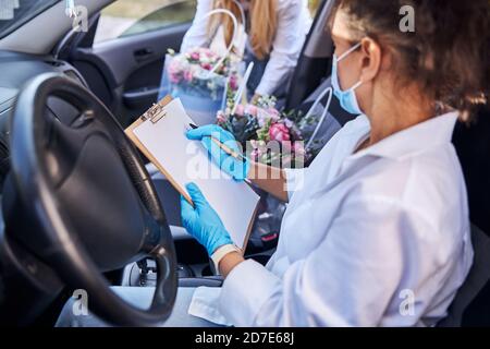 Fiorista femminile che ha un dovere di consegna del bouquet Foto Stock