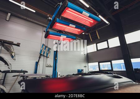 Asciugatura a infrarossi delle parti della carrozzeria dell'auto dopo l'applicazione di mastice e vernice nel reparto di riparazione carrozzeria. Foto Stock