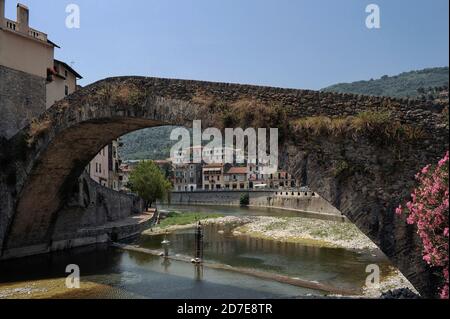 Il ponte Vecchio del XV secolo ad arco singolo o Ponte Vecchio a Dolceacqua, Imperia, Liguria, Italia ha un grazioso arco unico di 33 m / 108 piedi ‘ddorso della chiave’ che attraversa il fiume Nervia. È stato descritto nel febbraio 1884 dal fondatore dell'impressionismo francese Claude Monet come "un bijou de légèreté" (un gioiello di leggerezza). Due giorni dopo dipinse sia il ponte che il castello cinquecentesco di Doria, sulle pendici inferiori del Monte Rebupo, che domina Terra, il centro storico di Dolceaqua. Foto Stock