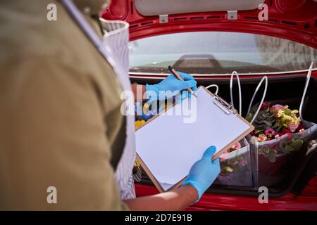 Scrittura maschile multirazziale su una carta di fronte ai fiori Foto Stock