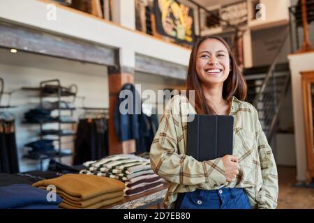 Ritratto di una donna proprietaria di un negozio di moda che utilizza un tablet digitale Per controllare le scorte nel negozio di abbigliamento Foto Stock