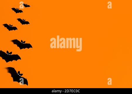 Sfondo arancione con un gregge di pipistrelli di carta nera per Halloween, silhouette di pipistrelli di carta nera su sfondo arancione, concetto di Halloween, copyspace Foto Stock