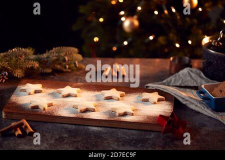 Biscotti di Natale appena sfornati a forma di stella su scheda spolverati con Zucchero a velo Foto Stock