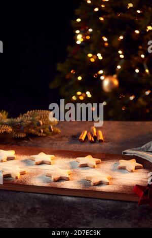 Biscotti di Natale appena sfornati a forma di stella su scheda spolverati con Zucchero a velo Foto Stock