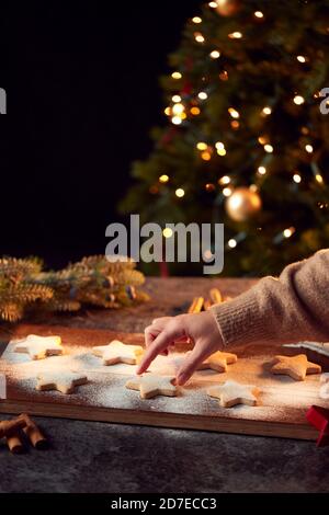 La mano delle donne raggiunge i biscotti di Natale a forma di stella appena sfornati A bordo spolverato con zucchero a velo Foto Stock