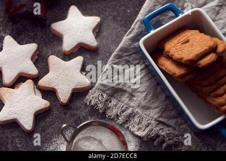 Biscotti di Natale appena sfornati a forma di stella su scheda spolverati con Zucchero a velo Foto Stock