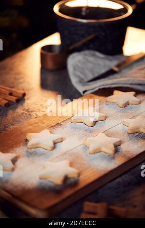 Biscotti di Natale appena sfornati a forma di stella su scheda spolverati con Zucchero a velo Foto Stock