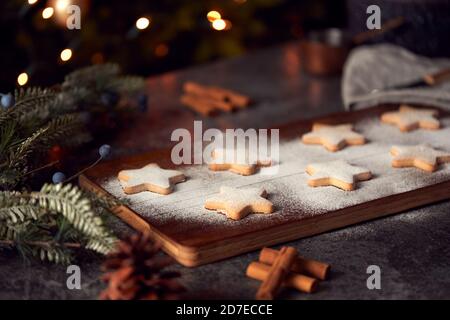 Biscotti di Natale appena sfornati a forma di stella su scheda spolverati con Zucchero a velo Foto Stock