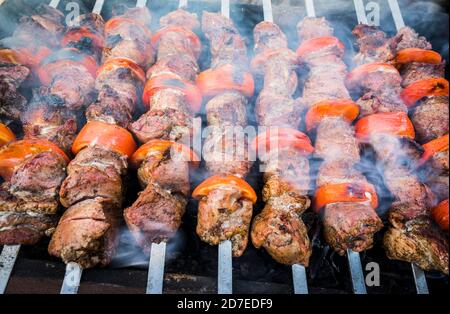 Carne per barbecue e pomodori sugli spiedini cosparsa di pepe, durante la frittura Foto Stock