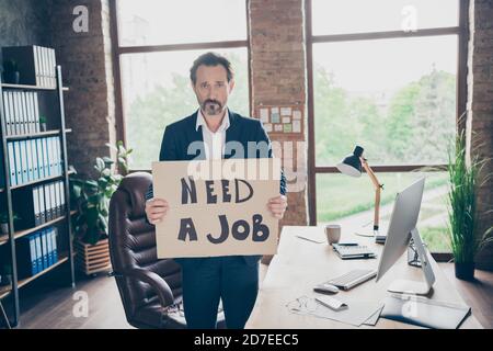 Ha bisogno di un lavoro. Foto di profilo della disperazione moody licenziato lavoratore d'ufficio ragazzo maturo tenendo cartellone in cerca di nuovo lavoro ultimo giorno di lavoro lavoro Foto Stock