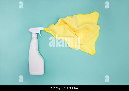 Flacone di detergente in plastica spray bianco su fondo verde con panno giallo. Foto Stock