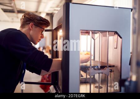 Studente universitario maschile che studia ingegneria utilizzando la macchina di stampa 3D Foto Stock