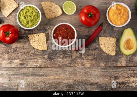 Salse messicane tradizionali. Guacamole, salsa al peperoncino e salsa al formaggio su tavola di legno Foto Stock