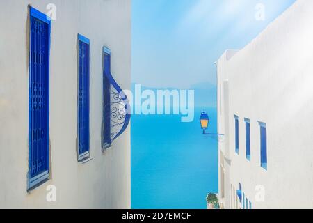 Vista mare blu tra le case su una strada stretta in Sidi Bou Said, Tunisia. Giugno 2019 Foto Stock
