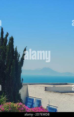 Vista blu sul mare e sulle montagne attraverso i tetti di Sidi Bou Said, Tunisia Foto Stock