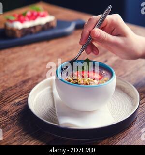 Donna che mangia dessert di frutta con un cucchiaio in un caffè estivo, primo piano Foto Stock