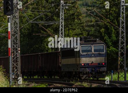 Treno elettrico blu sotto le montagne di Vysoke Tatry in estate mattina soleggiata Foto Stock