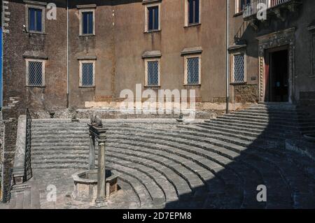 La facciata curva del rinascimentale Palazzo colonna Barberini a Palestrina, Lazio, segue il profilo del façade secolo d.C. Tempio Romano di Fortuna Primigenia. I resti del tempio furono incorporati in un palazzo costruito nel 1043 d.C. dalla potente dinastia colonna. Fu distrutta e ricostruita due volte prima di passare alla famiglia Barberini nel 1630. L'arco monumentale di scalini che si elevava all'ingresso del palazzo un tempo portava al tempio, che sorgeva nella città romana di Praeneste, un rifugio estivo preferito dai ricchi romani. Il palazzo è oggi un museo archeologico. Foto Stock