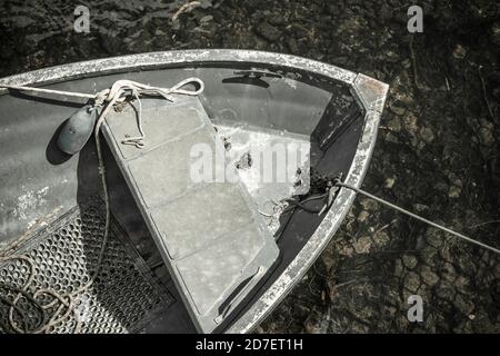 Vista dall'alto dell'arco di una piccola barca a vela ormeggiata a banchina. È stato quasi totalmente desaturato per dare una sensazione monocromatica. Foto Stock