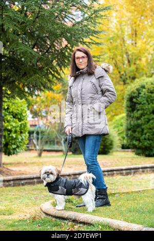 Donna che cammina nel parco con il suo cane nel pioggia Foto Stock