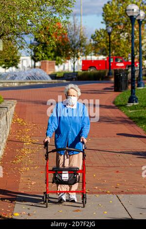 Frederick, MD, USA 10/14/2020: Una donna caucasica molto anziana sta passeggiando in un parco usando il suo camminatore a rotelle in una giornata di sole autunno. Indossa una maschera facciale Foto Stock