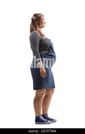 Foto di profilo di lunghezza intera di una giovane donna incinta dentro un abito in denim isolato su sfondo bianco Foto Stock