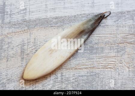 pendente osseo su sfondo grigio in legno Foto Stock