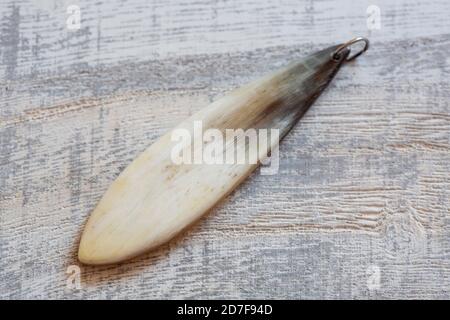 pendente osseo su sfondo grigio in legno Foto Stock